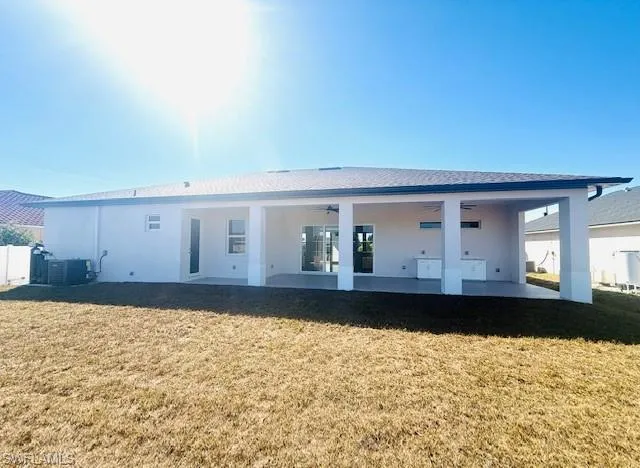 Back of house with a lawn, stucco siding, a patio area, and ceiling fan