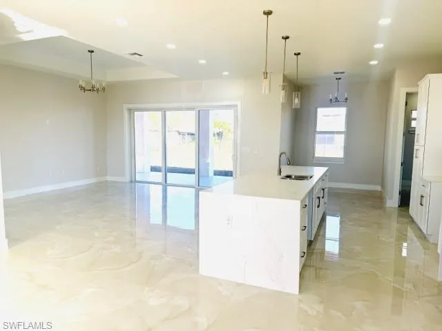 Empty room featuring a raised ceiling, crown molding, and hanging lights