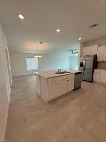 Kitchen featuring white cabinets, fridge, recessed lighting, hanging light fixtures, and dishwasher