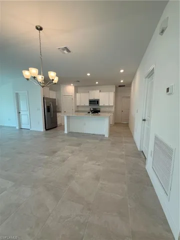 Kitchen featuring recessed lighting, light countertops, open floor plan, fridge, and an island with sink