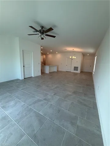 Unfurnished living room featuring a chandelier, ceiling fan, and recessed lighting
