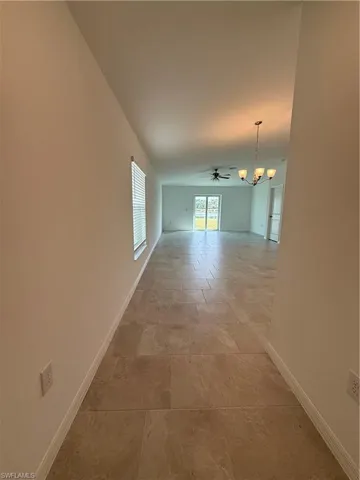 Spare room featuring ceiling fan and a chandelier