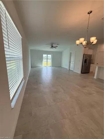 Unfurnished living room with ceiling fan and a chandelier