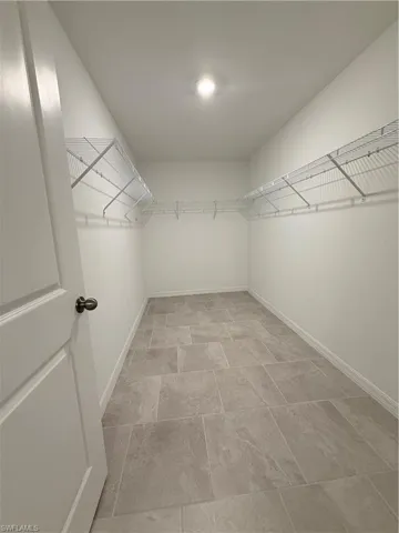 Walk in closet featuring stone finish floors