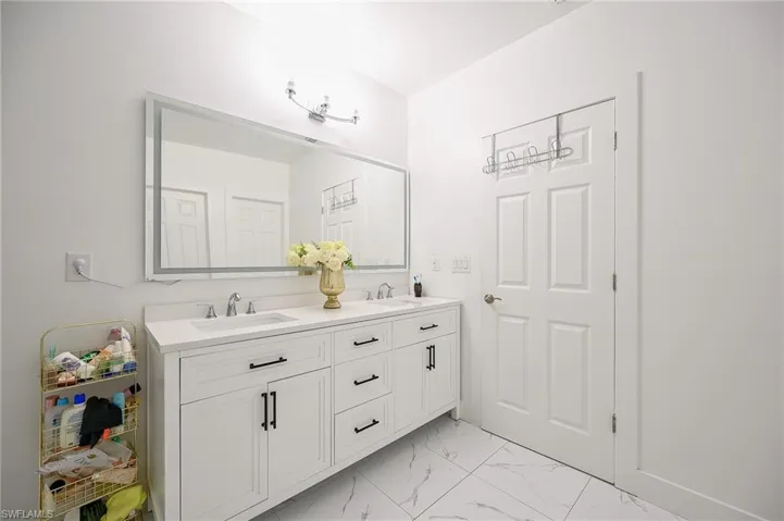 Double vanity with integrated sinks and white cabinetry, featuring dark hardware