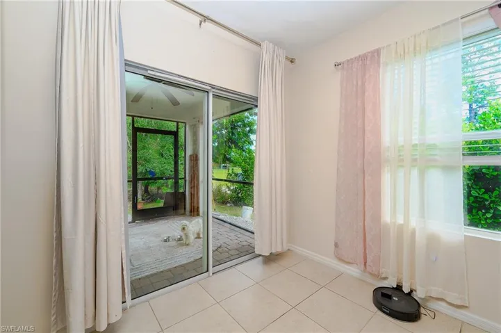 Tiled flooring throughout this room, featuring direct access to a screened patio and a window with horizontal blinds