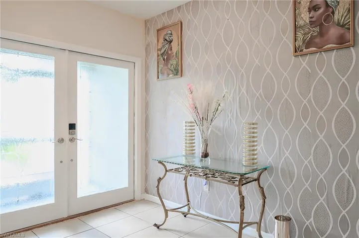 Entryway featuring double French doors with frosted glass panels, a digital smart lock, tiled flooring, and a textured accent wall