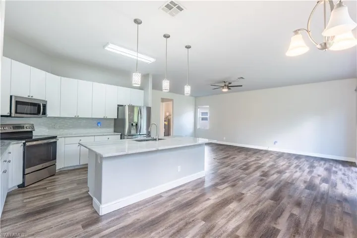 Kitchen featuring stainless steel appliances, hanging light fixtures, a ceiling fan, and open floor plan