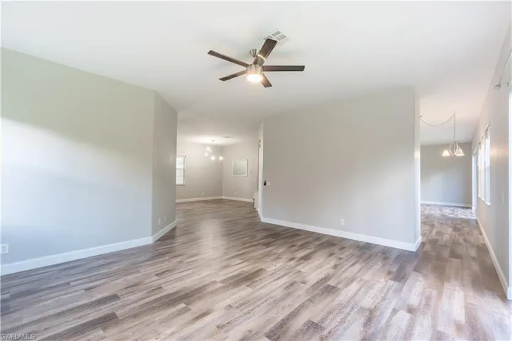 Unfurnished formal living room featuring a chandelier, light wood-style flooring, and ceiling fan