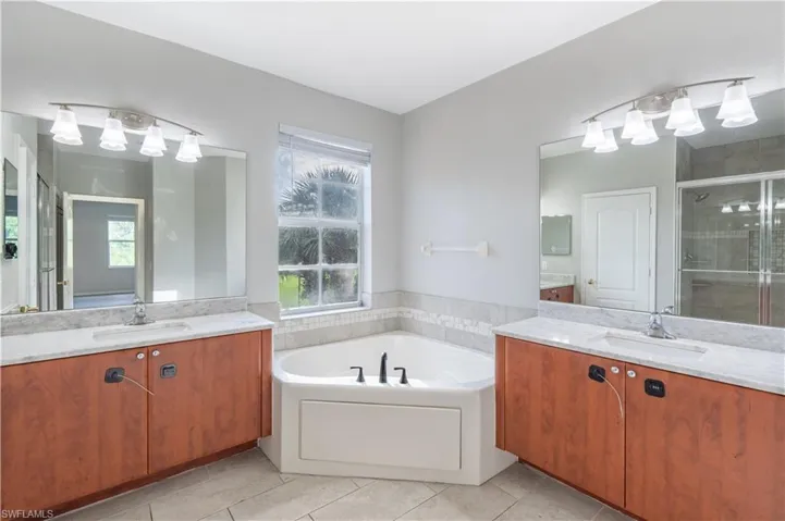 Master bathroom featuring healthy amount of natural light, two vanities, and a shower stall