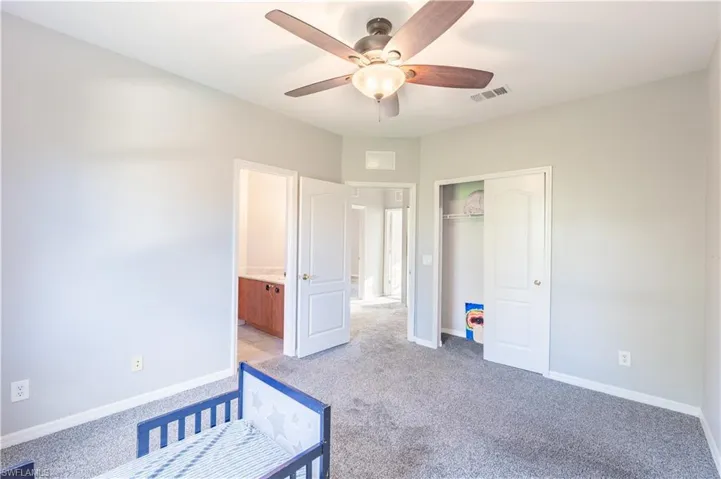 Carpeted bedroom 4 with light colored carpet, ensuite bath, ceiling fan, and a closet