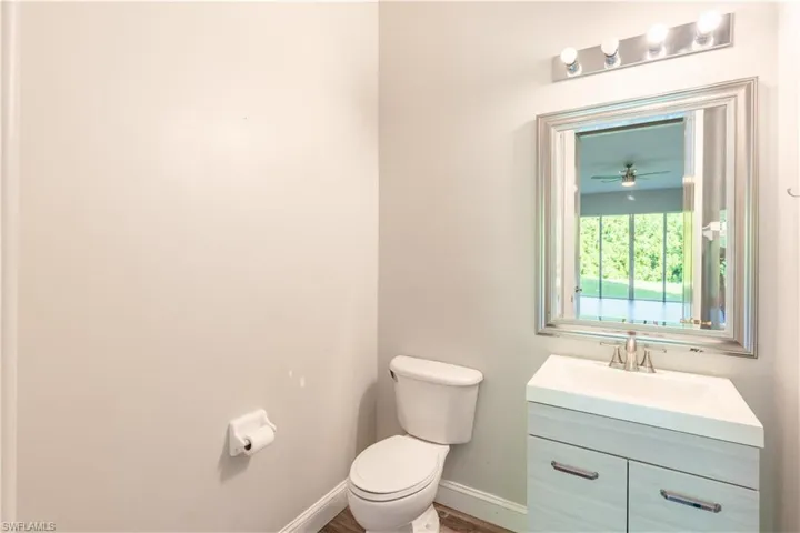 Downstairs Half bathroom with vanity, a ceiling fan, and wood finished floors