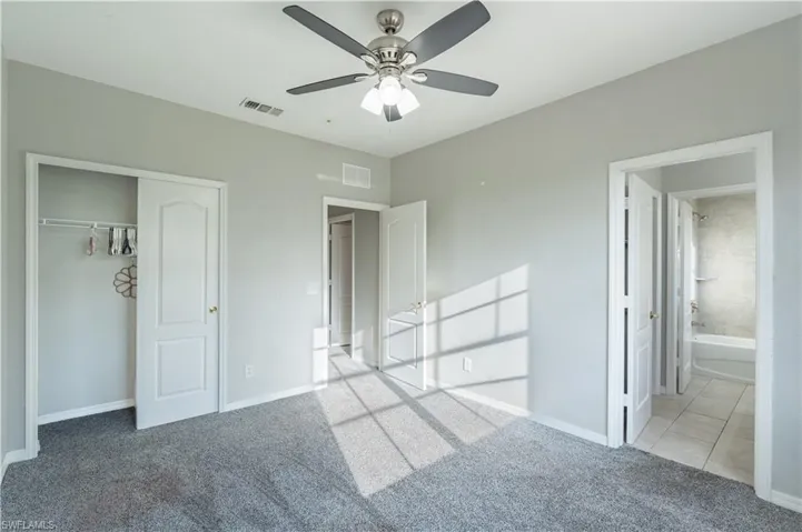 Unfurnished bedroom 3 featuring carpet, ceiling fan, a closet, tile patterned flooring, and connected bathroom