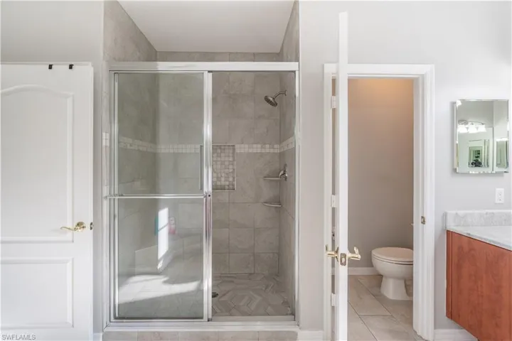 Master bathroom with vanity, a shower stall, and light tile patterned floors