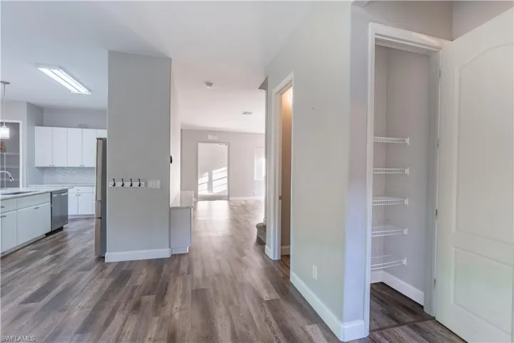Second pantry. Kitchen with white cabinetry, dark wood-style floors, backsplash, decorative light fixtures, and appliances with stainless steel finishes