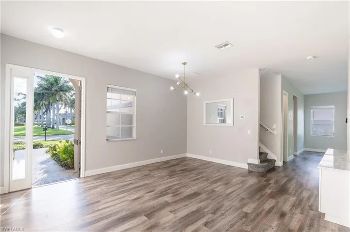 Unfurnished living room featuring dark wood-type flooring, a chandelier, and stairway