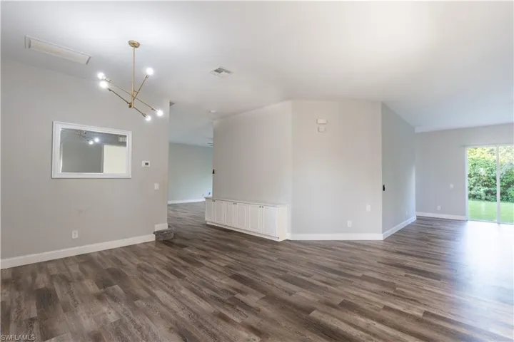 Unfurnished room featuring a chandelier, dark wood-style flooring, and a ceiling fan