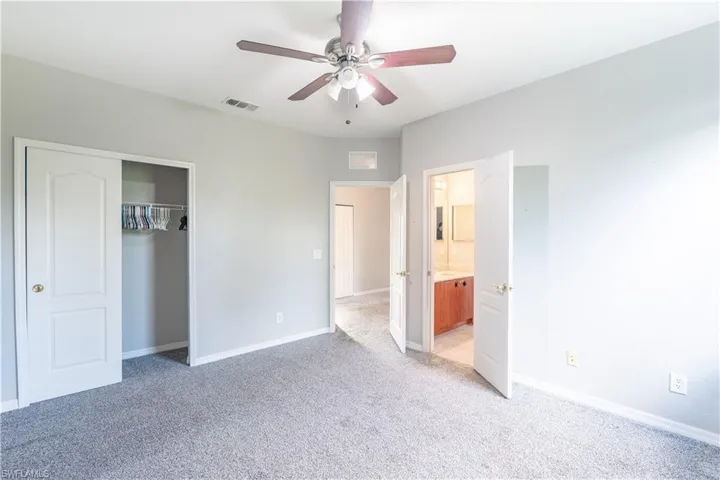 Unfurnished bedroom 5 featuring light colored carpet, ceiling fan, a closet, and ensuite bath