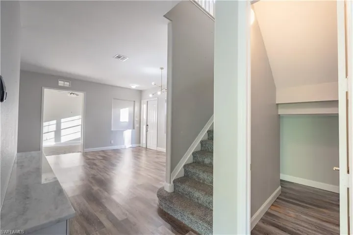 Stairs featuring wood finished floors and baseboards with small storage room beneath straits
