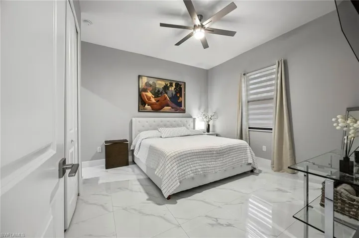 Spacious room featuring large format tile flooring, a modern ceiling fan, and a window with blinds and drapes