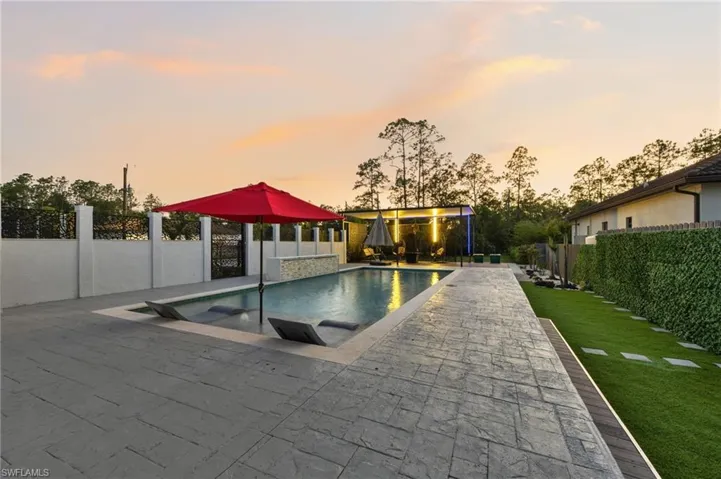 Resort-style pool area featuring stamped concrete decking, sun shelf with in-pool loungers