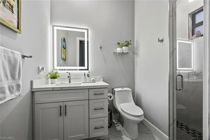 Contemporary bathroom featuring a single vanity with a white countertop and light gray cabinetry