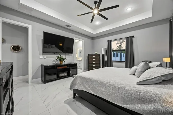 Primary bedroom featuring recessed lighting, a tray ceiling, and a contemporary ceiling fan
