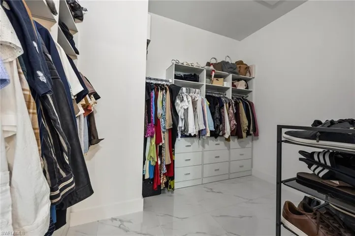Walk in closet featuring white cabinetry, built-in shelving, hanging rods, and drawer storage