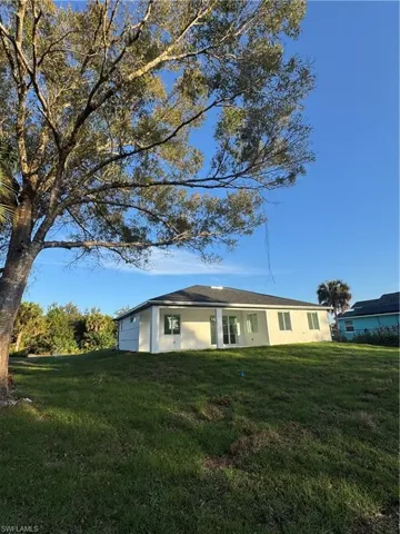 Rear view of property with a lawn and stucco siding