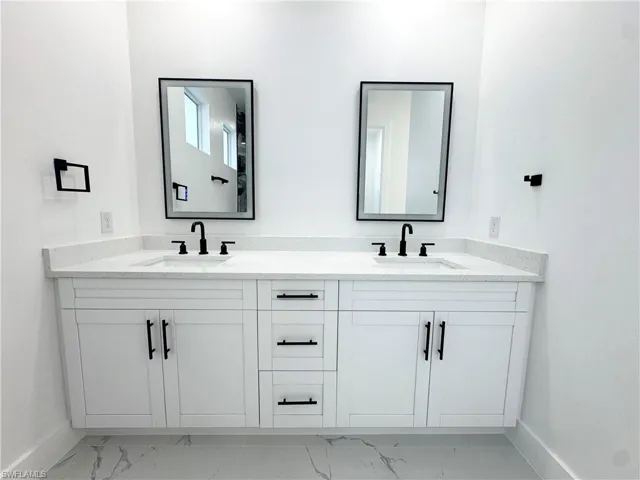 Full bathroom featuring double vanity and light marble finish flooring