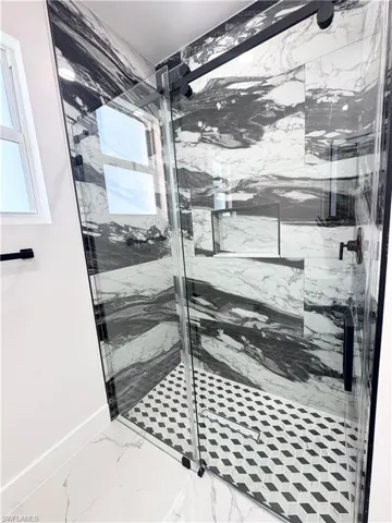Bathroom with a marble finish shower and light marble finish floors