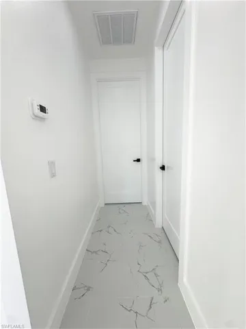 Hallway featuring light marble finish floors and baseboards