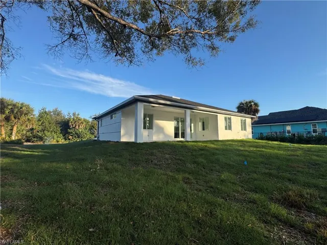 Back of house featuring a lawn and stucco siding
