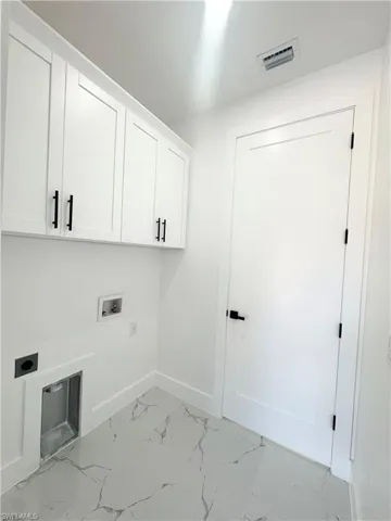 Laundry area featuring light marble finish floors, hookup for a washing machine, cabinet space, and electric dryer hookup