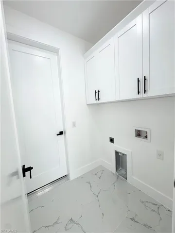 Washroom with light marble finish floors, electric dryer hookup, washer hookup, and cabinet space
