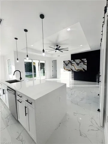 Kitchen featuring light marble finish flooring, white cabinetry, a barn door, a raised ceiling, and recessed lighting