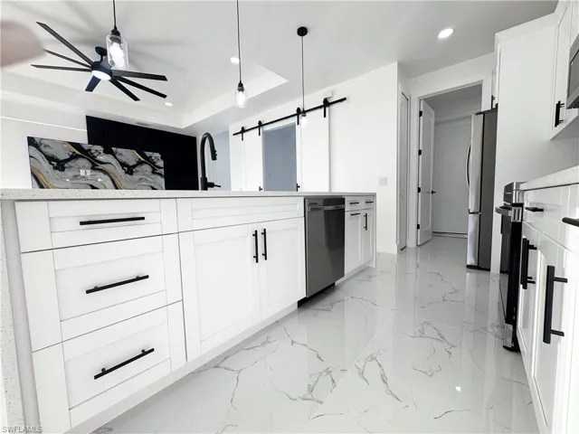 Kitchen featuring white cabinets, recessed lighting, a barn door, pendant lighting, and ceiling fan
