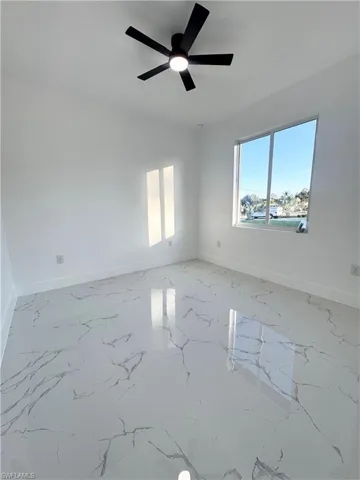Spare room with marble tiled floors and a ceiling fan