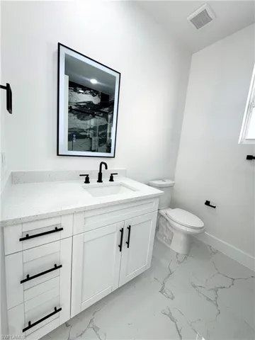 Bathroom with light marble finish floors, vanity, and a marble finish shower