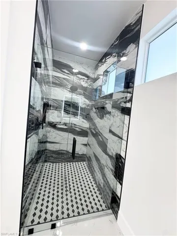Full bath with a marble finish shower