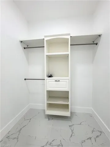 Walk in closet featuring light marble finish flooring