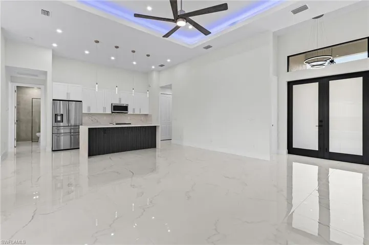 Kitchen featuring appliances with stainless steel finishes, ceiling fan, white cabinetry, open floor plan.