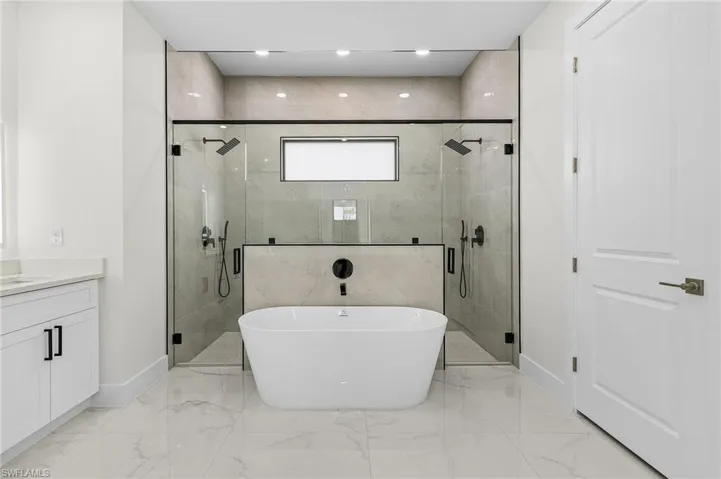 Master bathroom with a stall shower, baseboards, vanity, a freestanding bath, and porcelain floors