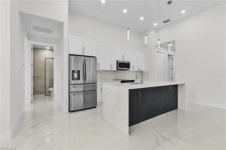 Kitchen with marble finish floor, a sink, white cabinetry, and stainless steel appliances