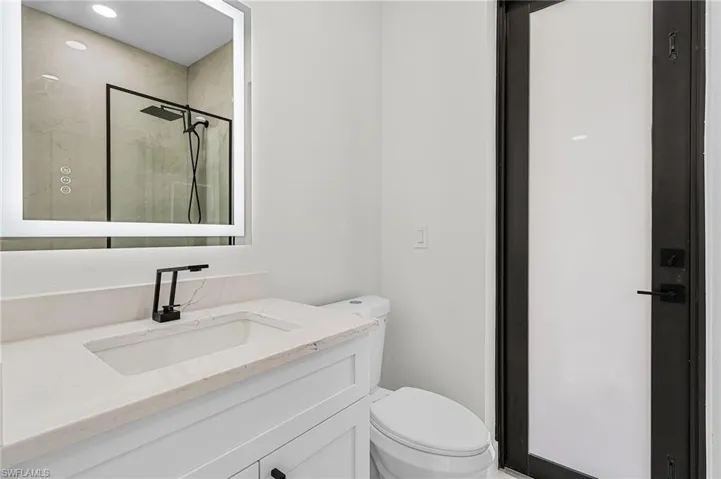 Pool bathroom with vanity, toilet, and a stall shower