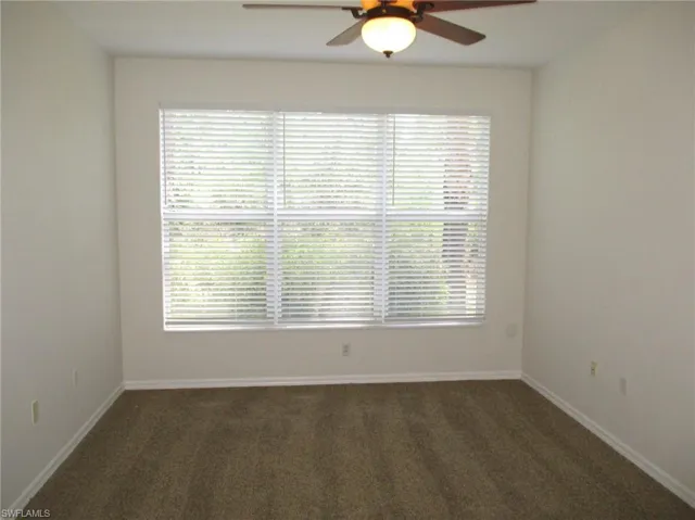 Carpeted spare room with a wealth of natural light and ceiling fan