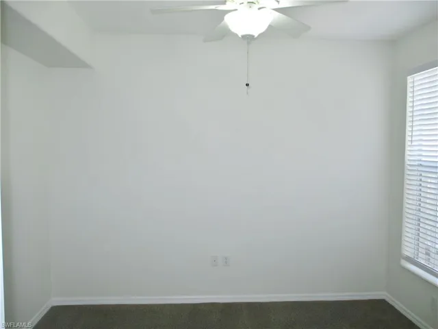 Carpeted spare room featuring ceiling fan