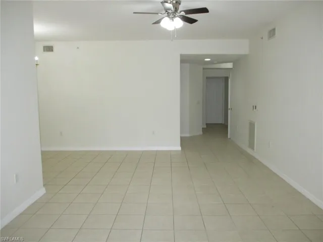Empty room with ceiling fan and light tile floors