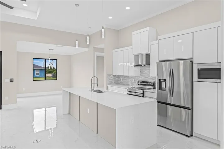 Kitchen with stainless steel appliances, light marble finish floors, decorative light fixtures, crown molding, and modern cabinets