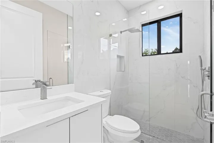 Bathroom featuring vanity and a marble finish shower
